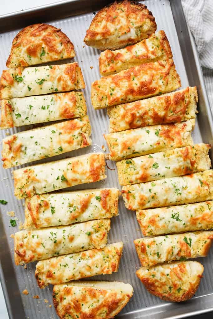 Cheesy garlic bread on a French Loaf on half baking sheet