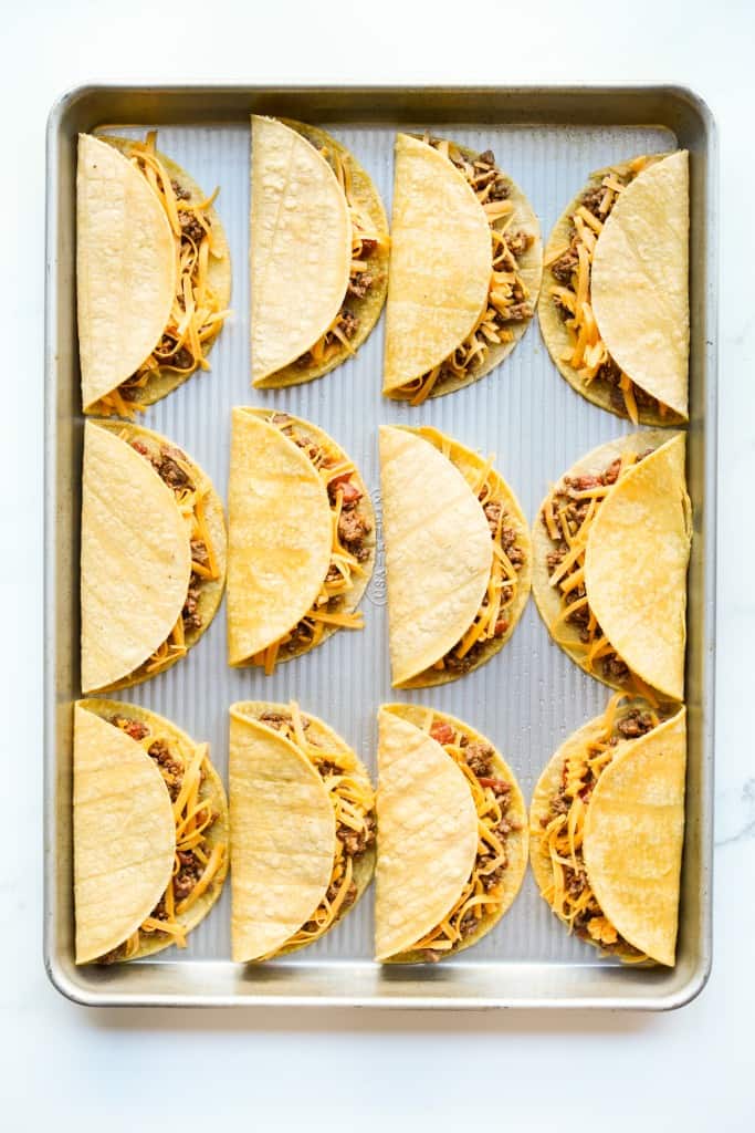 Corn tortillas stuffed with ground beef on a sheet pan