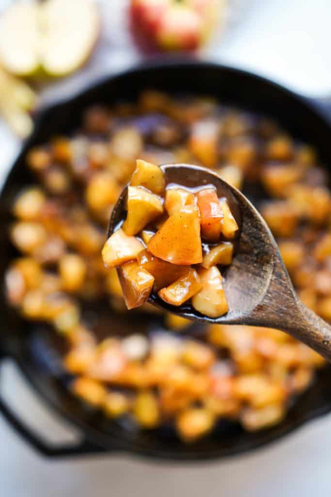 Scooping up caramelized apples with a wooden spoon