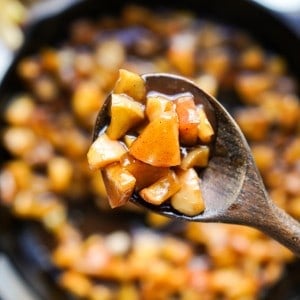 Picking up fried apple in cinnamon brown sugar glaze using a wooden spoon