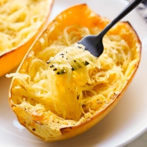 Using a fork to lift up spaghetti squash strands from a large squash