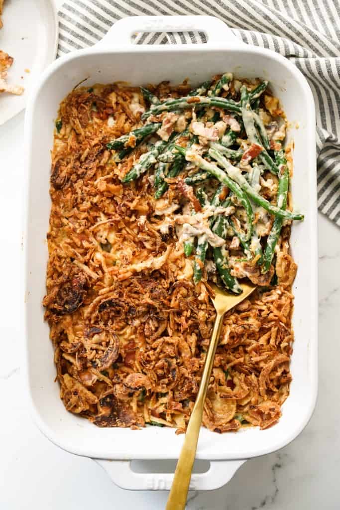 A casserole dish of green beans smothered in mushroom cream sauce topped with crispy onions