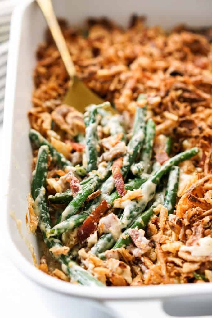 Green bean casserole with bacon topped with crispy onions in a baking dish