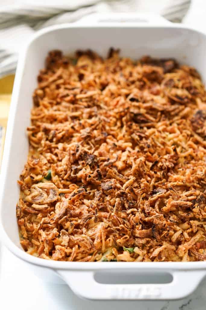 Green bean casserole topped with fried onions fresh off the oven in a casserole dish