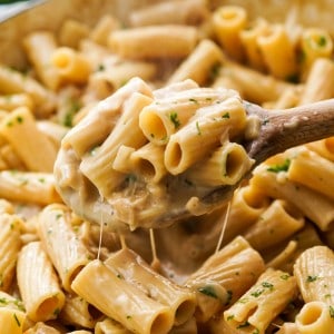 Lifting up creamy French Onion Pasta with a wooden spoon