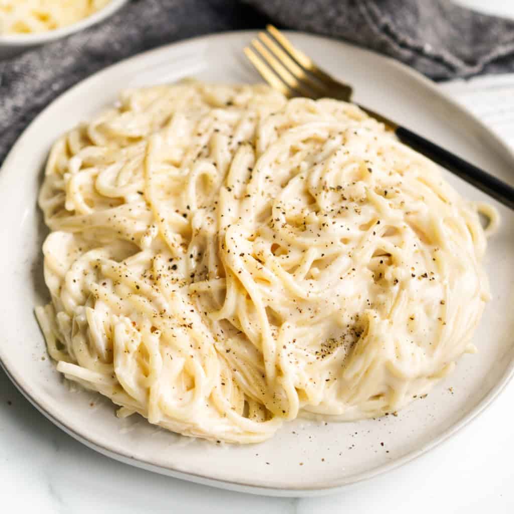 A plate of spaghetti mac and cheese topped with crack black pepper