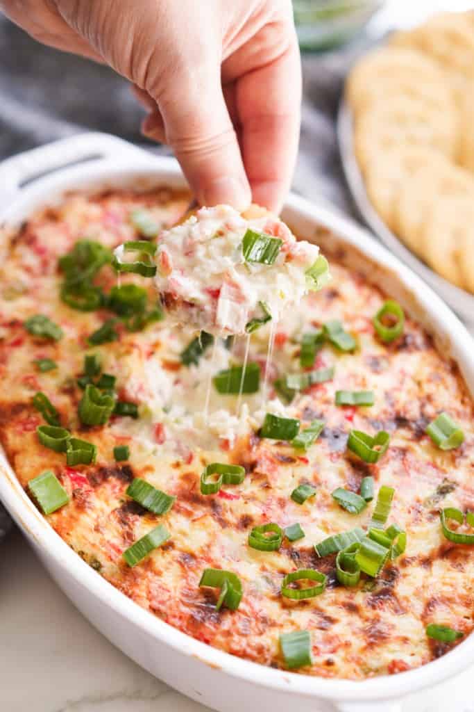 Using a cracker to dip into warm crab rangoon dip