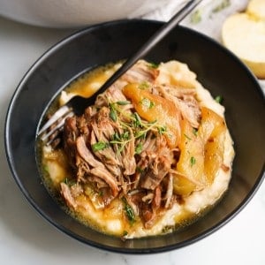 A bowl of apple braised pork on top of mashed potatoes in a bowl