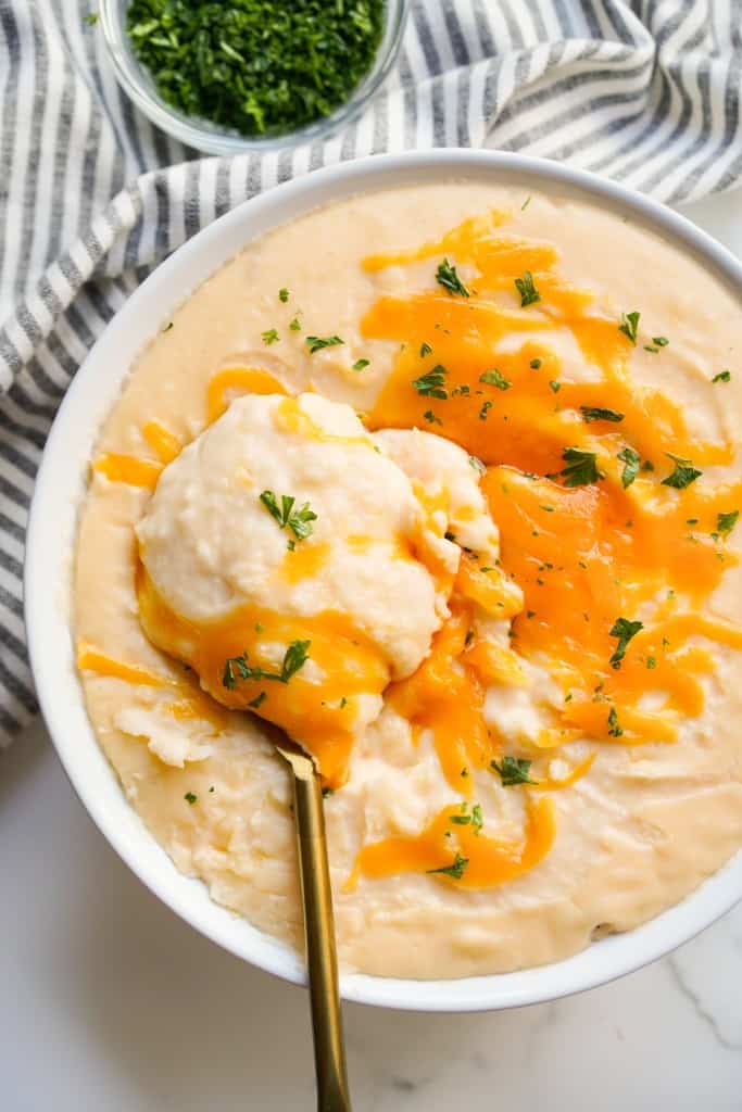 Scooping out a bowl of mashed potatoes topped with melted cheese