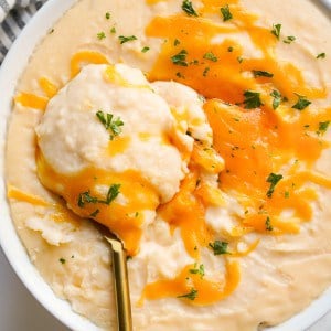 Scooping out cheesy mashed potatoes from a bowl