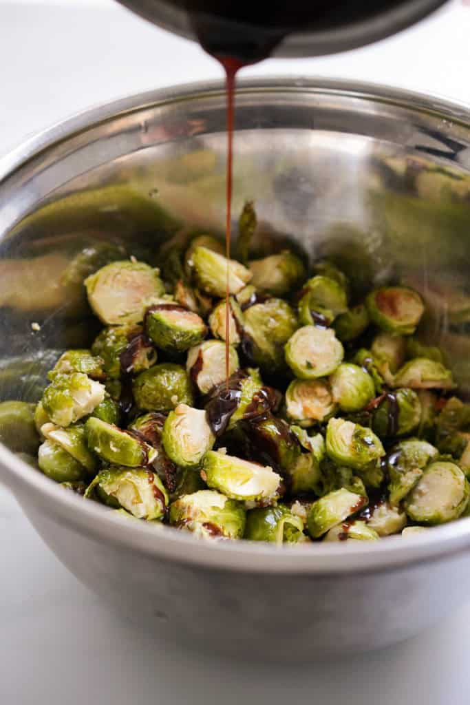 Drizzling thick balsamic glaze onto brussels sprouts