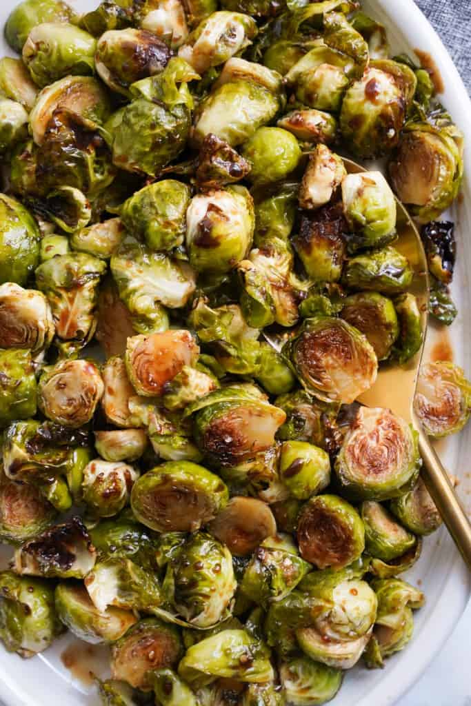 Scooping up roasted brussels sprouts with honey balsamic glaze