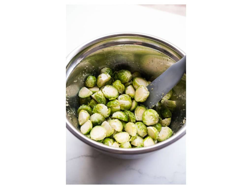 Brussels sprouts tossed in garlic, salt and olive oil in a mixing bowl