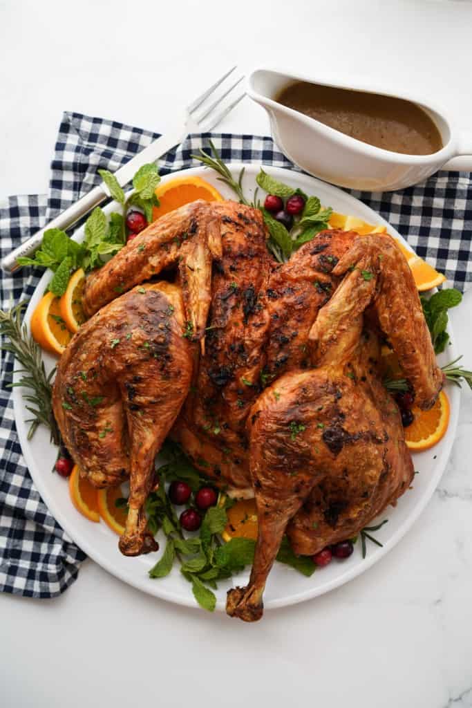 A large turkey butterflied and spread out on a large round platter