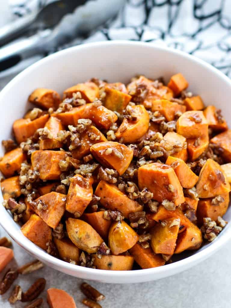 A bowl of cubed caramelized sweet potatoes tossed with pecan pieces