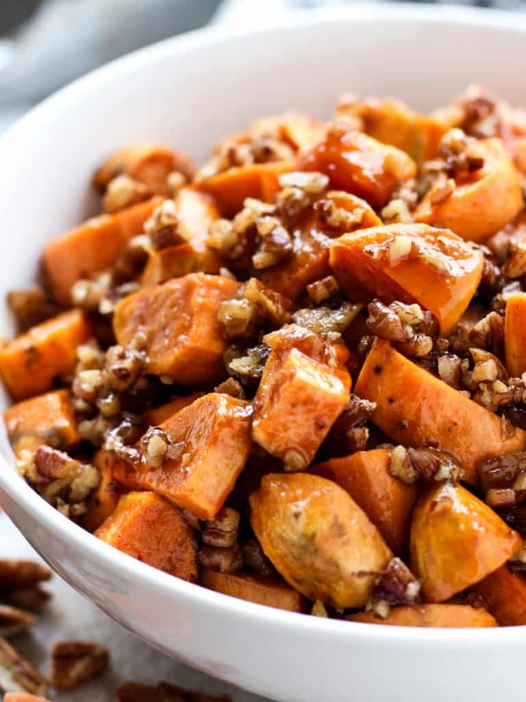 Brown Sugar Pecan Roasted Sweet Potatoes in a bowl with tongs in the background