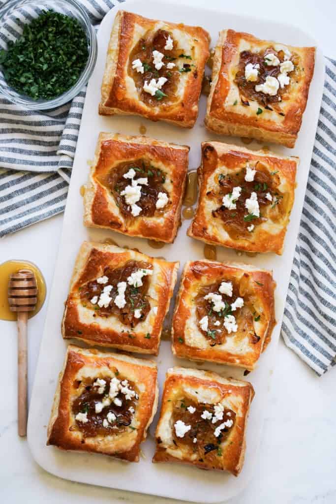 Top down view of a plate of caramelized onion goat cheese puff pastry bites
