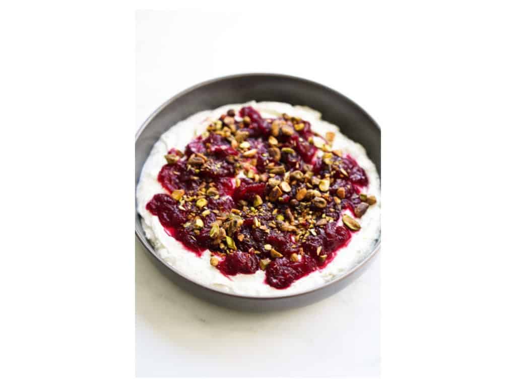 Whipped feta in a bowl, with cranberry sauce and crushed pistachios on top