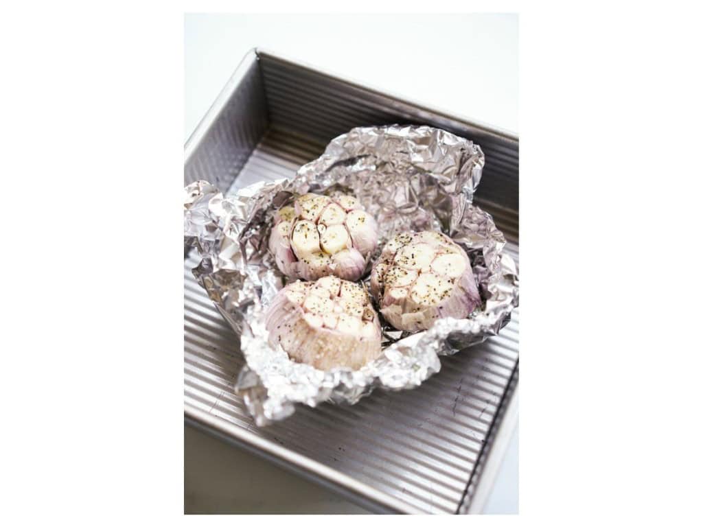 Garlic bulb drizzled in oil, salt and black pepper, wrapped in foil