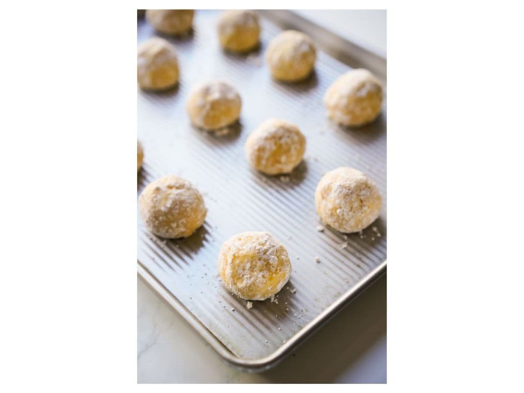 cookie dough covered in powdered sugar on baking sheet