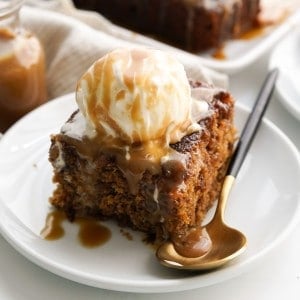 A slice of date cake topped with vanilla ice cream and toffee sauce.