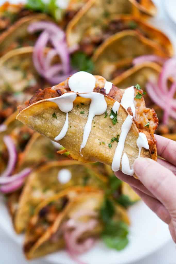 Holding a crispy chipotle chicken taco with more in the background