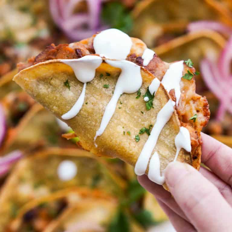 Holding a crispy chipotle chicken taco drizzled with sour cream