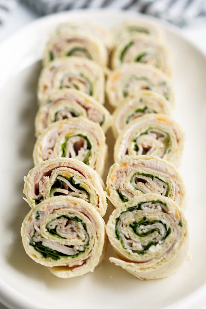Two rolls of turkey pinwheels rolled up in a flour tortilla with lettuce and cheese