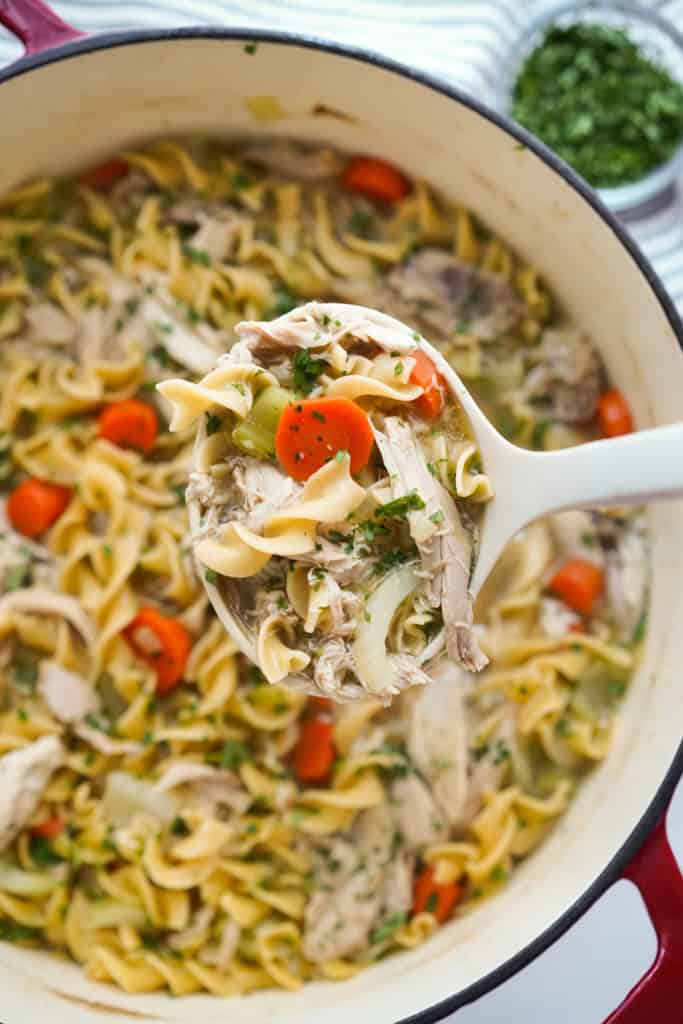 Using a ladle to scoop up a scoop of chicken noodle soup made from scratch