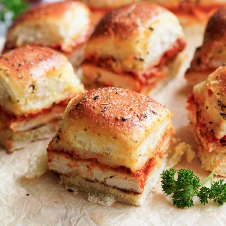 A zoomed in picture of Italian chicken sliders with an accent of curly leaf parsley.