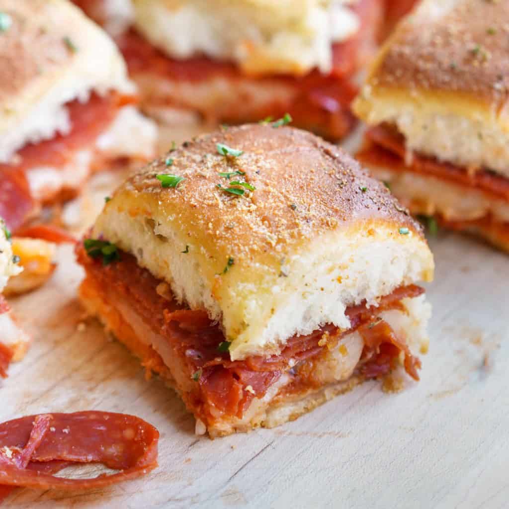 A zoomed in shot of a pizza slider that has pepperoni, mozzarella, and a perfectly browned top.