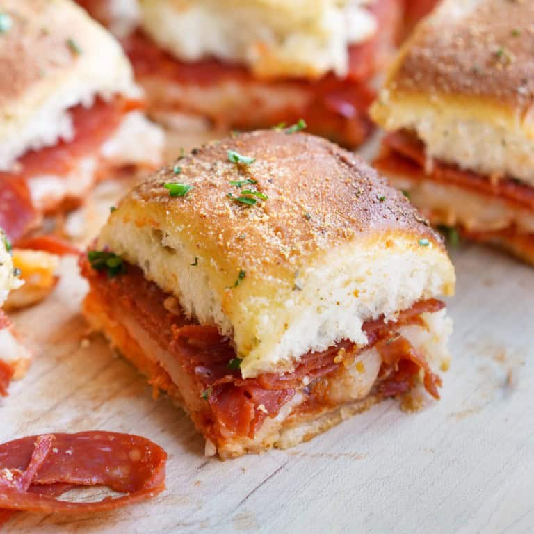 A zoomed in shot of a pizza slider that has pepperoni, mozzarella, and a perfectly browned top.