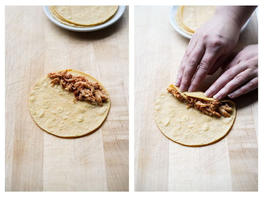 Chicken mixture is added to one side of a corn tortilla and then start rolling up the tortilla.
