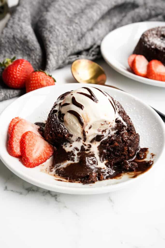 Gooey chocolate is pouring out of the center of a chocolate lava cake.
