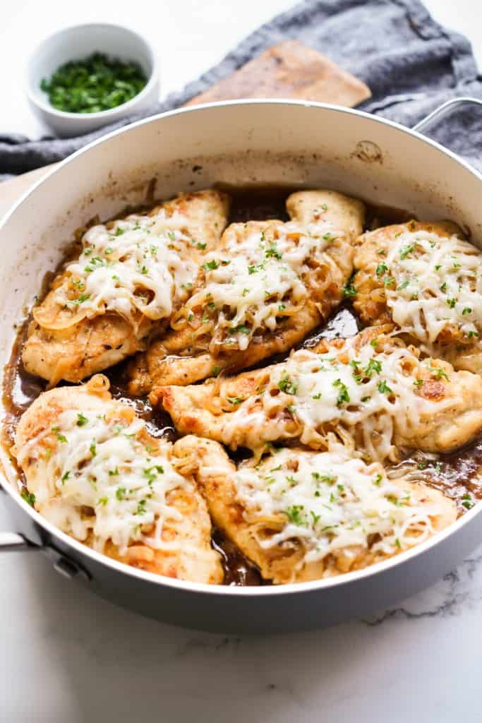 A deep-sided skillet filled with French Onion Chicken covered with melted cheese.