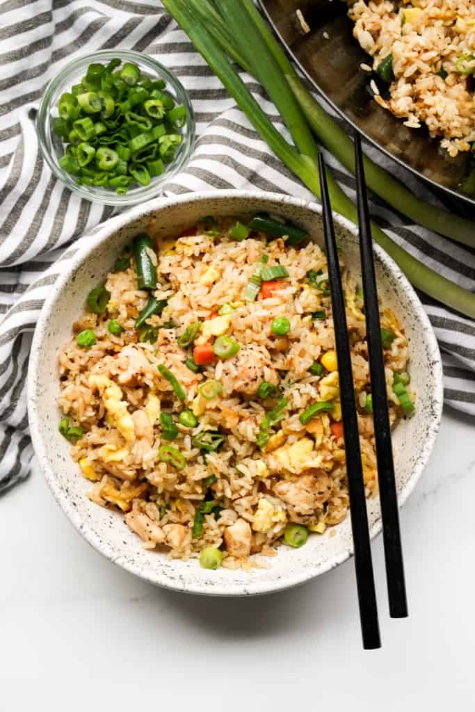 A bowl is filled with hibachi rice made at home with veggies and chicken breast.