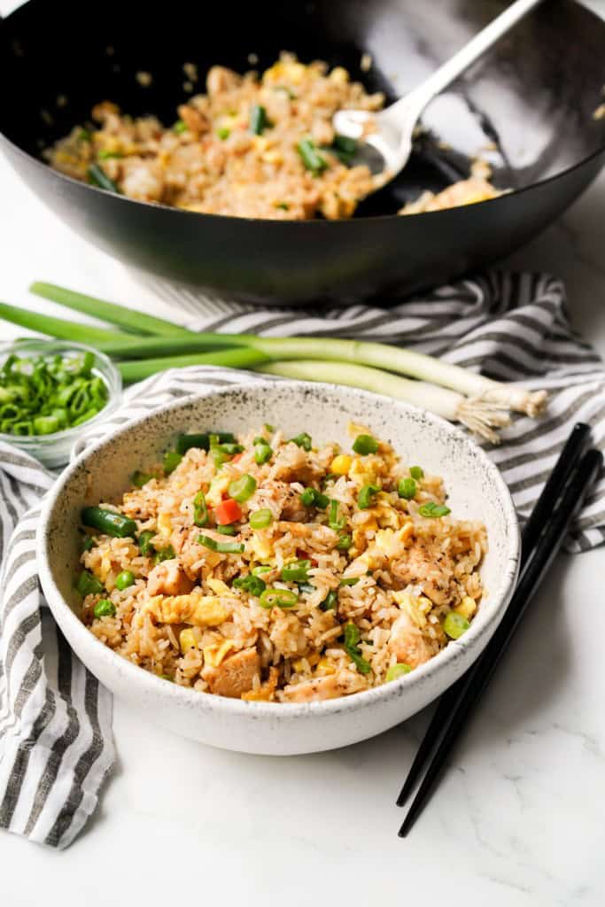 A bowl is filled with Japanese fried rice with a pair of chopsticks next to the bowl.