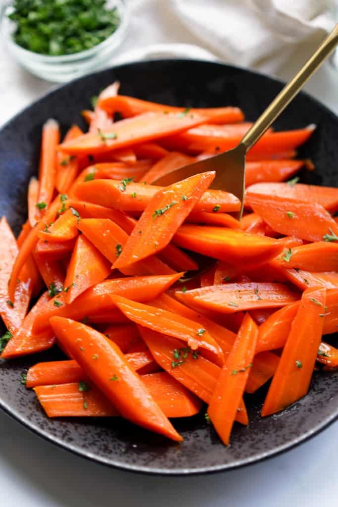 Scooping up candied carrots in a golden spoon.