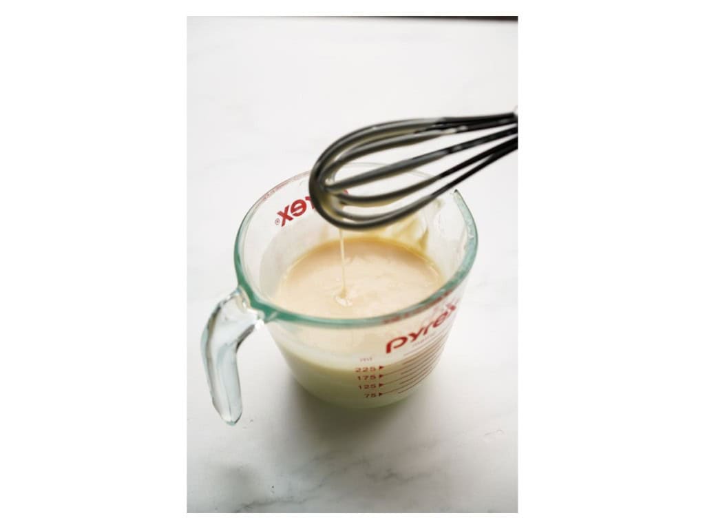 The dressing ingredients for the Broccoli Bacon Salad are added to a small measuring cup and then whisked together.