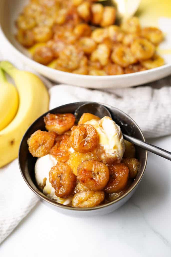A bowl full of vanilla ice cream is topped with brown sugar bananas.