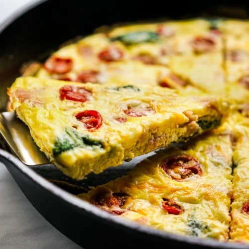 Egg frittata with tomatoes, spinach and ham in a cast iron skillet