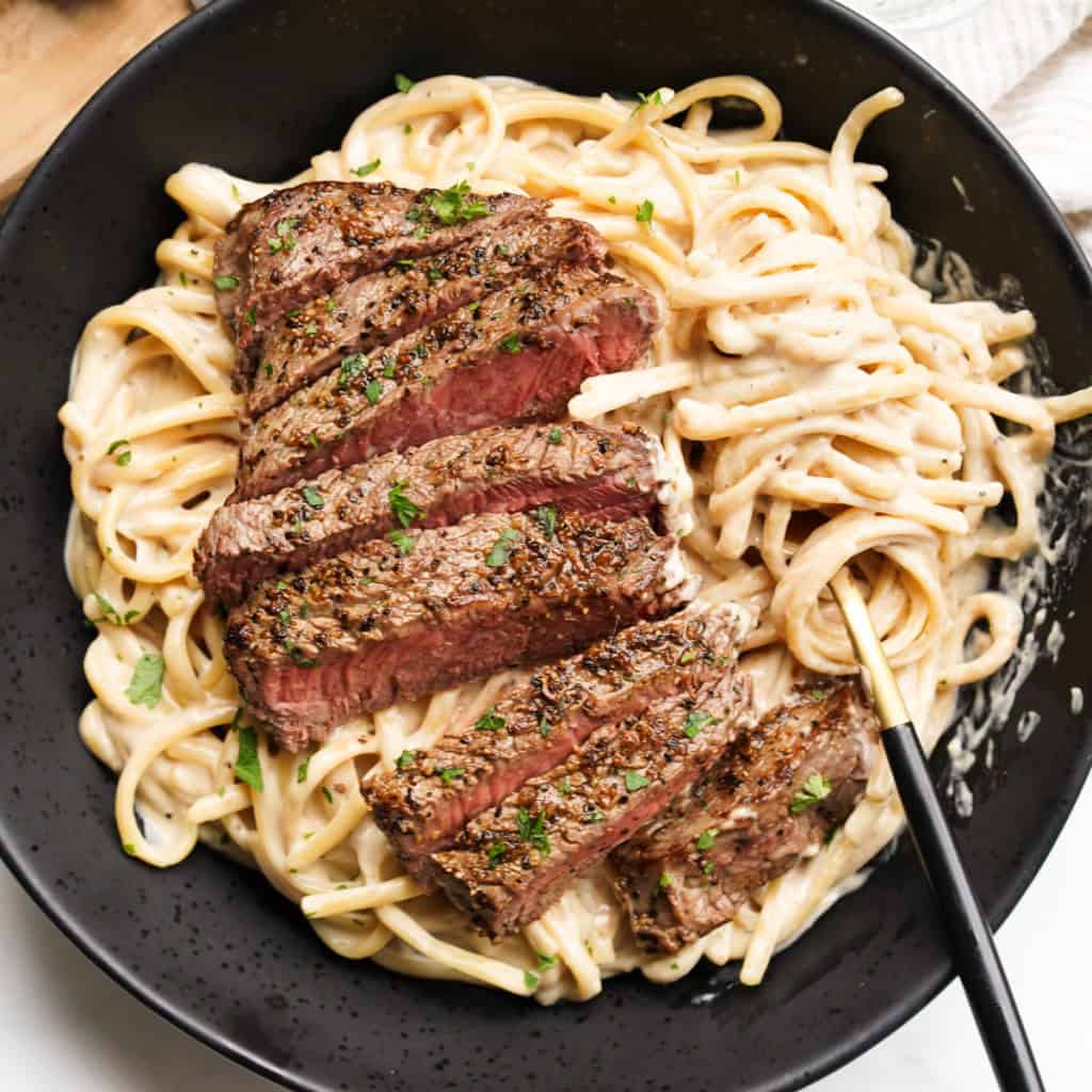 Creamy pasta is topped with steak strips.