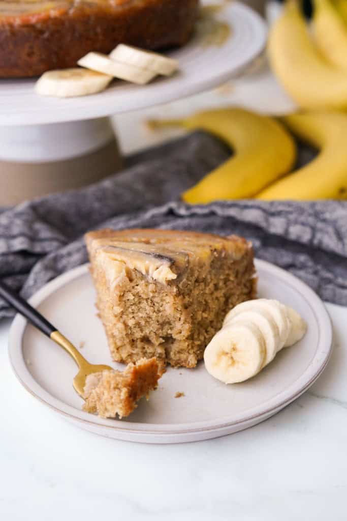 A fork has removed a bite from a slice of caramelized banana upside down cake.