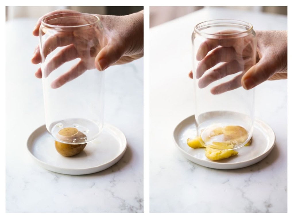The boiled potatoes are smashed with the flat bottom of a glass.
