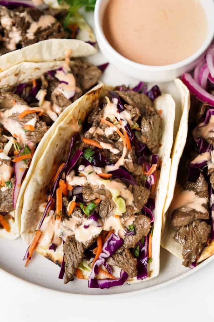 One of four Bulgogi Tacos is featured with a colorful slaw and sriracha mayo.