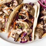A Korean BBQ Beef Taco stuffed with slaw and beef topped with a sriracha mayo drizzle.
