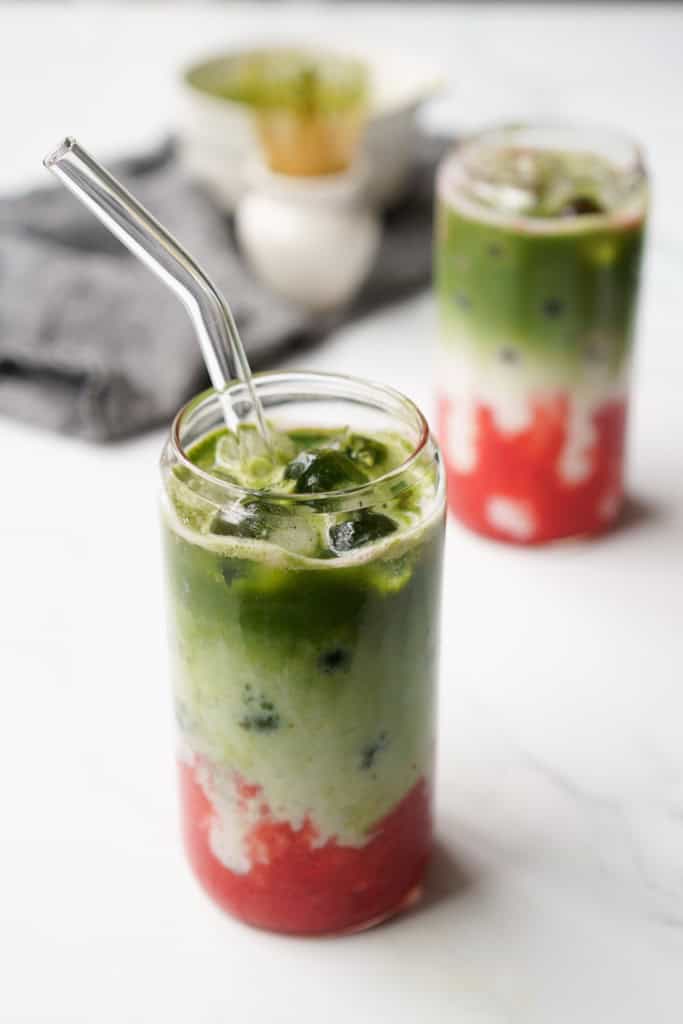 A straw is placed into an iced strawberry matcha latte.