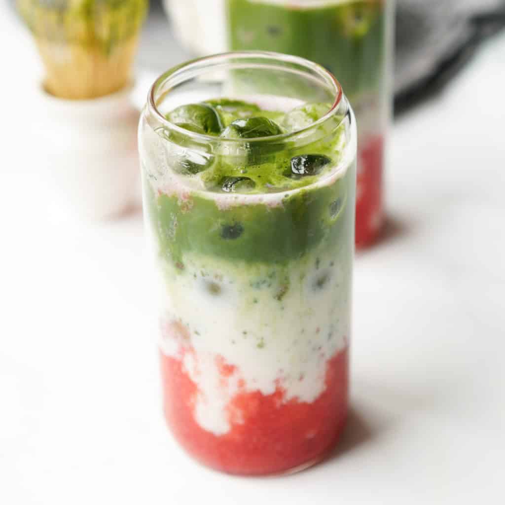 Strawberry Matcha is in a glass ready to be mixed and drank.