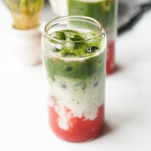 Strawberry Matcha is in a glass ready to be mixed and drank.