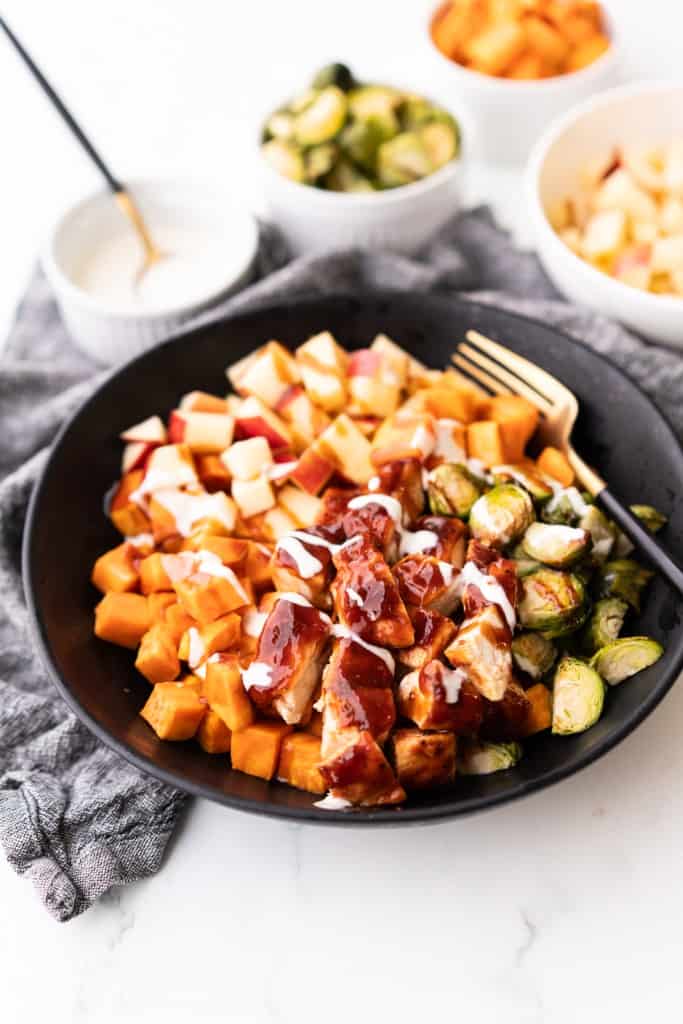 Chicken coated in bbq sauce along with sweet potatoes are mixed with brussels sprouts and diced apples and then topped with a ranch dressing drizzle.